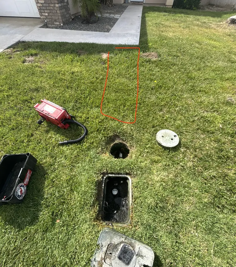 Acoustic leak detection equipment set up on a front lawn beside an open water meter box, with the suspected leak area marked in orange
