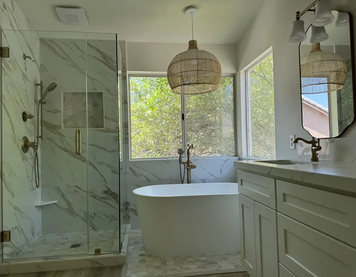 Finished bathroom remodel with a freestanding tub, glass-enclosed marble shower and brushed brass fixtures