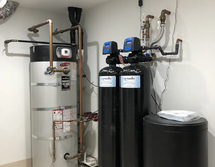 Newly installed gas tank water heater in a utility room beside a whole-house water softening system